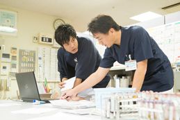 パソコン見ながら確認し合う看護部男性スタッフ2名
