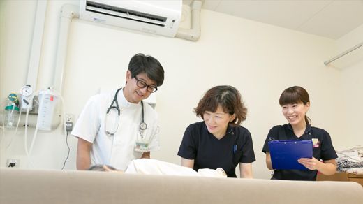ベッドに横たわる患者を話す医師と看護師