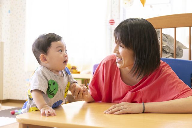 向き合う保育士と泯江堂エンゼル保育園園児