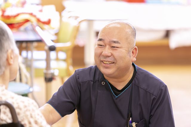 油山病院、高齢者に話しかける男性看護補助者